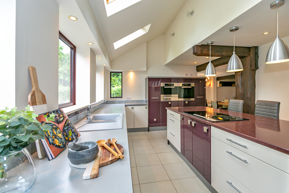 На фото: п-образная кухня в современном стиле с двойной мойкой, плоскими фасадами, белыми фасадами, белым фартуком, островом, белым полом, фиолетовой столешницей и мойкой у окна