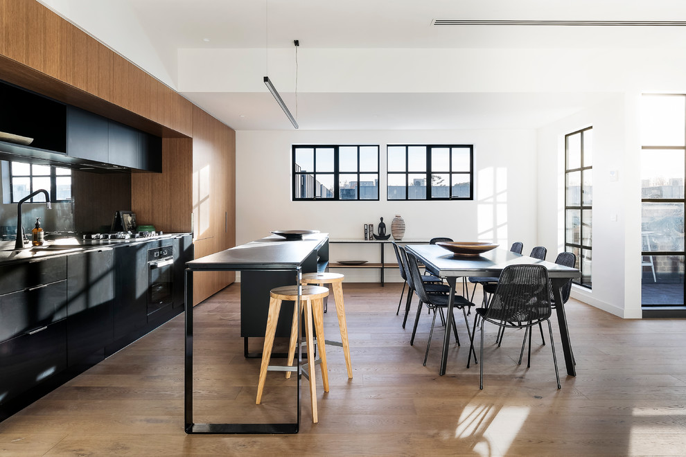 Ispirazione per una cucina design con ante lisce, ante nere, elettrodomestici neri, pavimento in legno massello medio e pavimento marrone