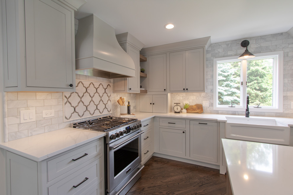Inspiration for a rural l-shaped open plan kitchen in Chicago with a belfast sink, beaded cabinets, grey cabinets, engineered stone countertops, marble splashback, stainless steel appliances, dark hardwood flooring, an island and white worktops.