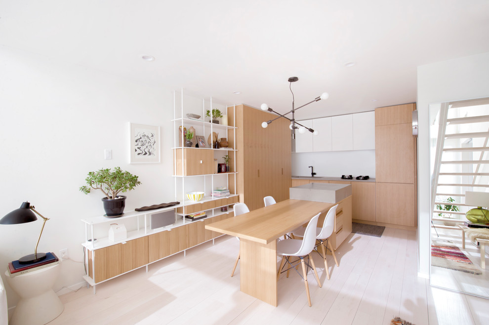 Inspiration for a contemporary l-shaped light wood floor and white floor eat-in kitchen remodel in New York with flat-panel cabinets, light wood cabinets, an island, an undermount sink, concrete countertops, paneled appliances and gray countertops