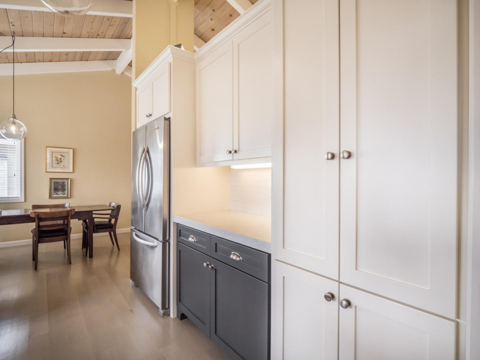 Bild på ett mellanstort funkis vit vitt kök, med en undermonterad diskho, skåp i shakerstil, grå skåp, marmorbänkskiva, vitt stänkskydd, stänkskydd i tunnelbanekakel, rostfria vitvaror, ljust trägolv, en halv köksö och grått golv