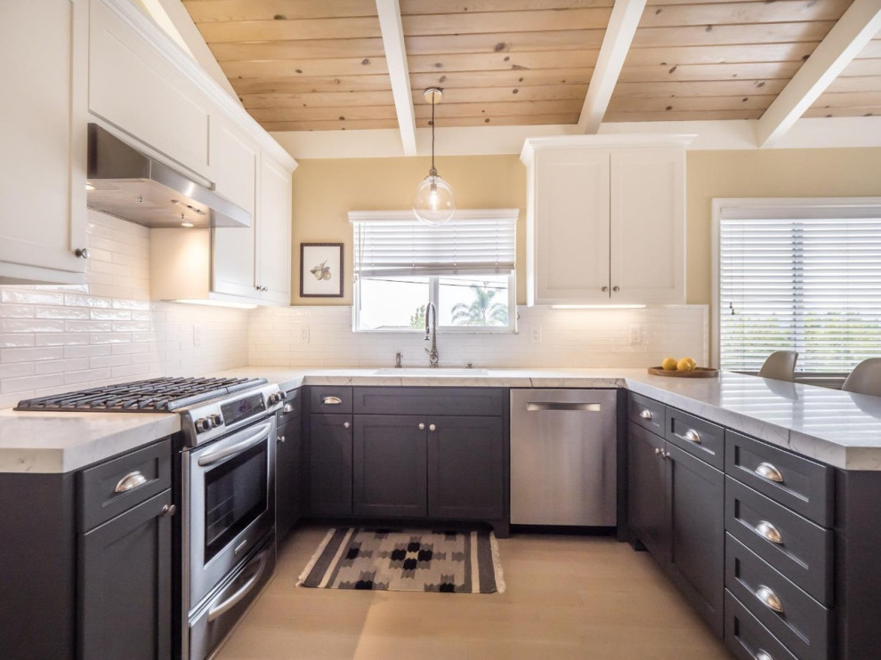 Inredning av ett modernt mellanstort vit vitt kök, med en undermonterad diskho, skåp i shakerstil, grå skåp, marmorbänkskiva, vitt stänkskydd, stänkskydd i tunnelbanekakel, rostfria vitvaror, ljust trägolv, en halv köksö och grått golv