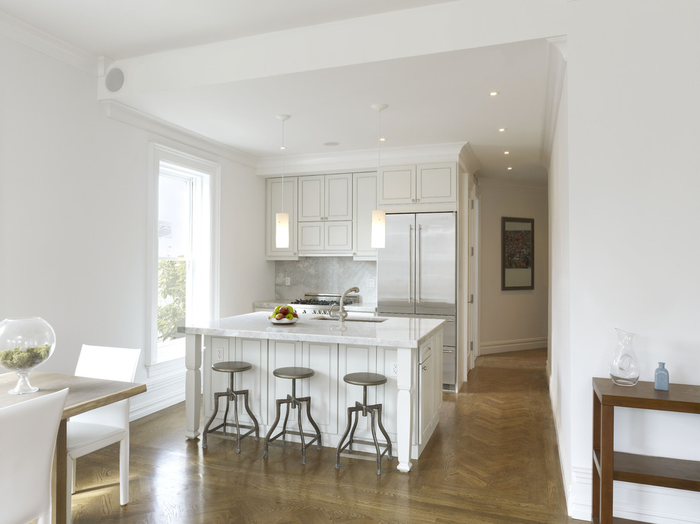 Example of a small trendy galley medium tone wood floor and brown floor eat-in kitchen design in New York with stainless steel appliances, an undermount sink, recessed-panel cabinets, white cabinets, quartzite countertops, stone slab backsplash, an island and gray backsplash
