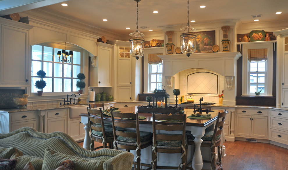 Klassisk inredning av ett mellanstort kök, med en rustik diskho, luckor med infälld panel, vita skåp, granitbänkskiva, vitt stänkskydd, stänkskydd i keramik, rostfria vitvaror, mellanmörkt trägolv och en köksö