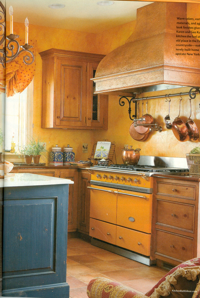 Exemple d'une grande cuisine montagne en U et bois vieilli fermée avec un évier encastré, un placard à porte affleurante, plan de travail en marbre, une crédence jaune, un électroménager de couleur, tomettes au sol et îlot.