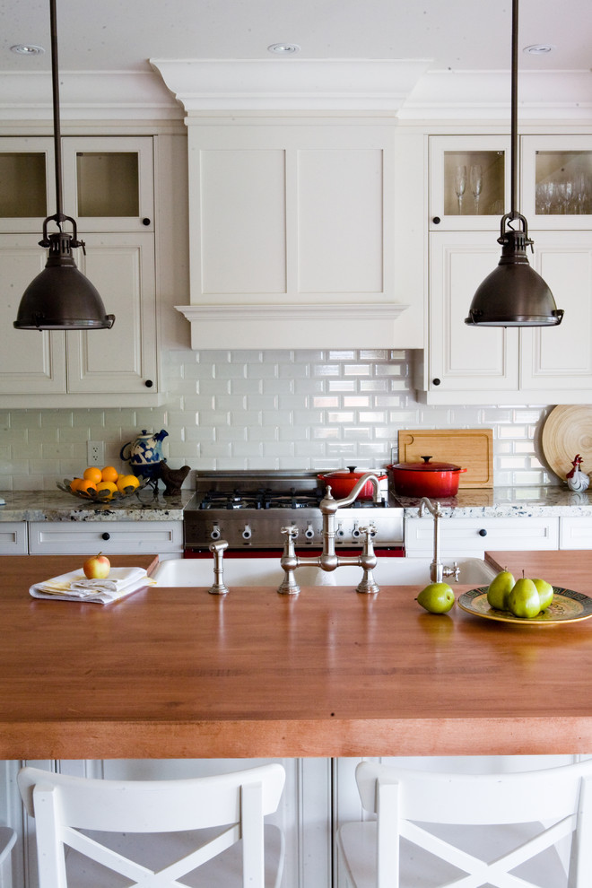 Example of a classic kitchen design in Toronto with wood countertops, a double-bowl sink, raised-panel cabinets, white cabinets, white backsplash and subway tile backsplash