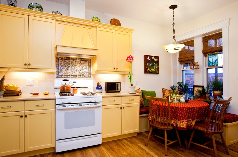 Источник вдохновения для домашнего уюта: кухня в классическом стиле с белой техникой, желтыми фасадами, обеденным столом и фасадами с утопленной филенкой