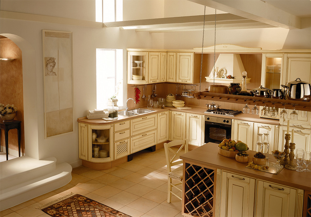 Example of a mid-sized french country l-shaped ceramic tile and beige floor eat-in kitchen design in San Diego with a double-bowl sink, beige backsplash, stainless steel appliances, an island, light wood cabinets, raised-panel cabinets, laminate countertops and wood backsplash