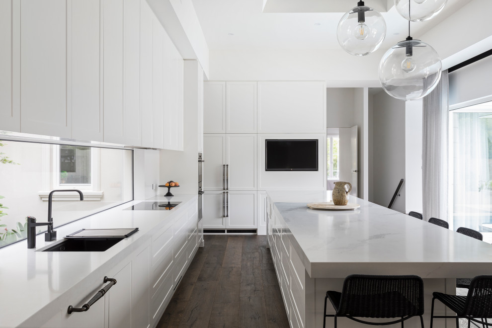 Idéer för att renovera ett stort vintage vit vitt l-kök, med en undermonterad diskho, skåp i shakerstil, vita skåp, fönster som stänkskydd, integrerade vitvaror, en köksö och brunt golv