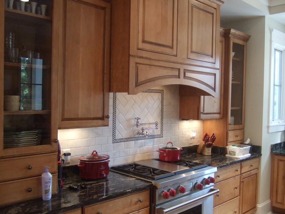 Foto på ett mellanstort vintage kök, med luckor med upphöjd panel, skåp i mellenmörkt trä, marmorbänkskiva, vitt stänkskydd, stänkskydd i tunnelbanekakel, rostfria vitvaror, klinkergolv i keramik, en köksö och beiget golv