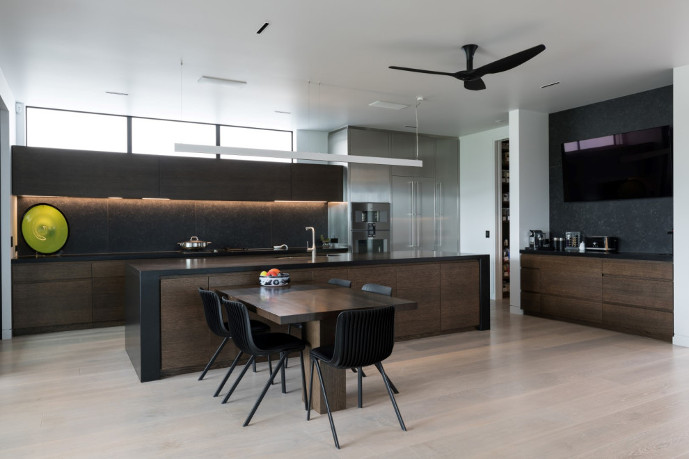 Inspiration for a large modern galley kitchen/diner in Other with a double-bowl sink, beaded cabinets, dark wood cabinets, composite countertops, black splashback, cement tile splashback, stainless steel appliances, light hardwood flooring, an island, beige floors and black worktops.