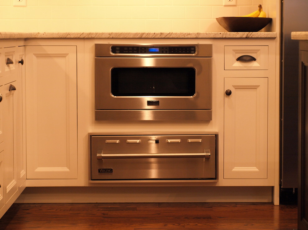 Example of a large classic u-shaped medium tone wood floor kitchen design in Newark with beaded inset cabinets, white cabinets, white backsplash, subway tile backsplash, stainless steel appliances and an island