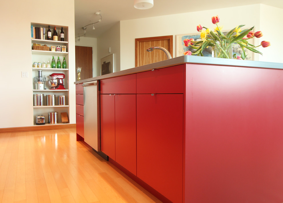 Exemple d'une petite cuisine ouverte moderne avec un évier encastré, un placard à porte plane, des portes de placard rouges, un plan de travail en surface solide, une crédence en dalle métallique, un électroménager en acier inoxydable, un sol en bois brun et îlot.