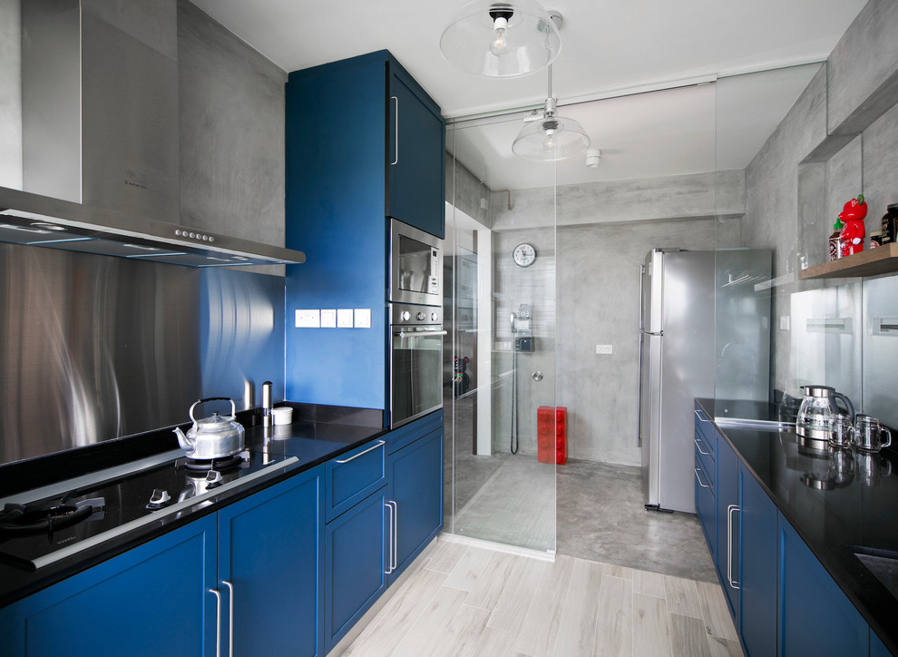 Design ideas for a medium sized urban enclosed kitchen in Singapore with a submerged sink, raised-panel cabinets, blue cabinets, black splashback, stone slab splashback, porcelain flooring and no island.