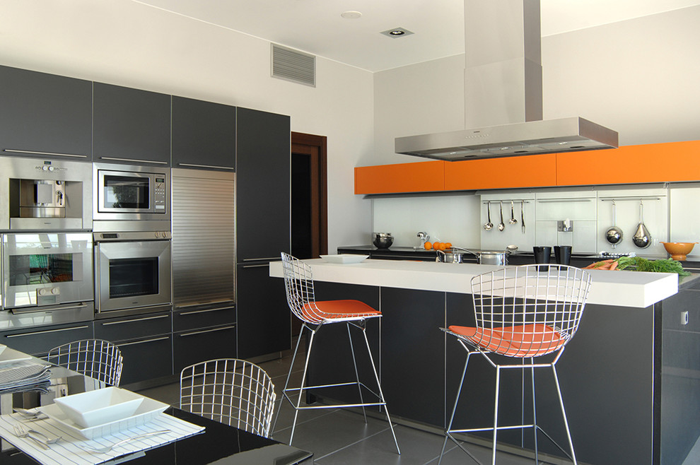 Esempio di una cucina contemporanea chiusa e di medie dimensioni con ante lisce, ante nere, top in superficie solida, paraspruzzi bianco, elettrodomestici in acciaio inossidabile e pavimento con piastrelle in ceramica
