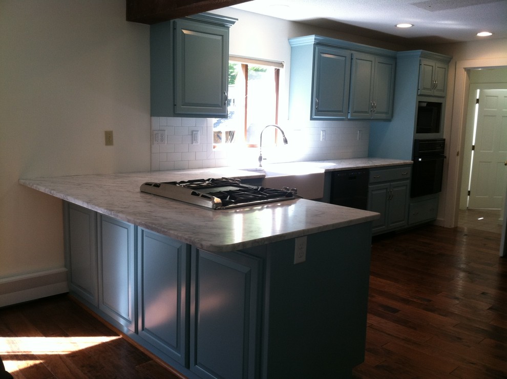 Country Wohnküche mit Landhausspüle, profilierten Schrankfronten, blauen Schränken, Marmor-Arbeitsplatte, Küchenrückwand in Weiß, Rückwand aus Metrofliesen und braunem Holzboden in Boston