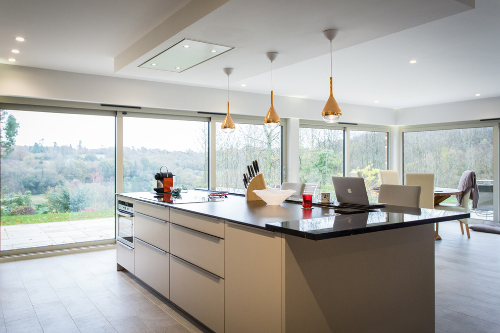 Photo of a large contemporary galley open plan kitchen in Hampshire with grey cabinets, marble worktops, metallic splashback, mirror splashback, stainless steel appliances, an island and flat-panel cabinets.