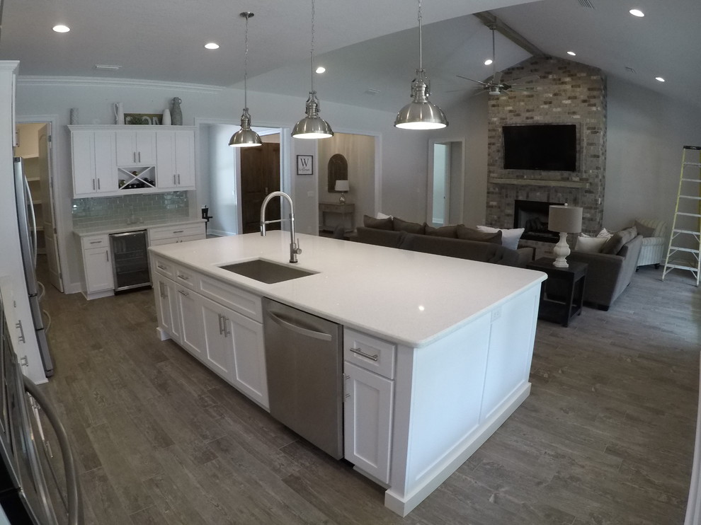 Inspiration for a mid-sized craftsman light wood floor and gray floor eat-in kitchen remodel in Miami with an undermount sink, shaker cabinets, white cabinets, quartz countertops, gray backsplash, glass tile backsplash, stainless steel appliances, an island and white countertops