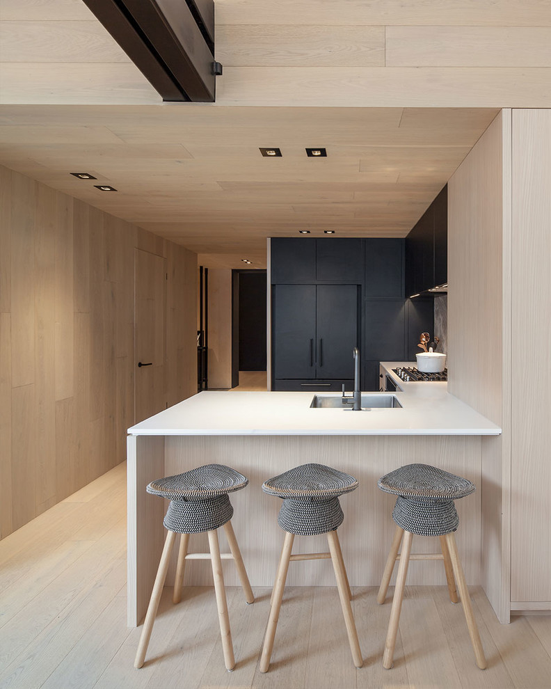 Example of a mid-sized minimalist u-shaped kitchen design in Toronto with an undermount sink, flat-panel cabinets, black cabinets, black appliances and a peninsula