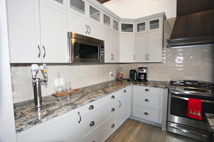 This is an example of a medium sized rural l-shaped kitchen/diner in Toronto with a submerged sink, shaker cabinets, grey cabinets, granite worktops, grey splashback, glass tiled splashback, stainless steel appliances, medium hardwood flooring and an island.