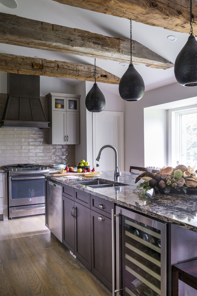 Inredning av ett lantligt mellanstort kök, med en undermonterad diskho, skåp i shakerstil, grå skåp, granitbänkskiva, grått stänkskydd, stänkskydd i tunnelbanekakel, rostfria vitvaror, mellanmörkt trägolv och en köksö