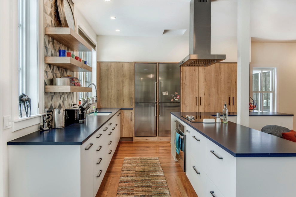 Moderne Küche mit Quarzwerkstein-Arbeitsplatte, blauer Arbeitsplatte, Unterbauwaschbecken, flächenbündigen Schrankfronten, hellen Holzschränken, bunter Rückwand, Küchengeräten aus Edelstahl, braunem Holzboden und Kücheninsel in Denver