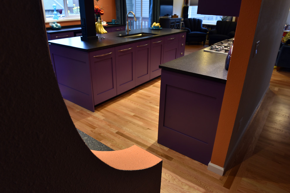Large eclectic galley light wood floor eat-in kitchen photo in Portland with an undermount sink, shaker cabinets, purple cabinets, solid surface countertops, orange backsplash, ceramic backsplash, stainless steel appliances and an island
