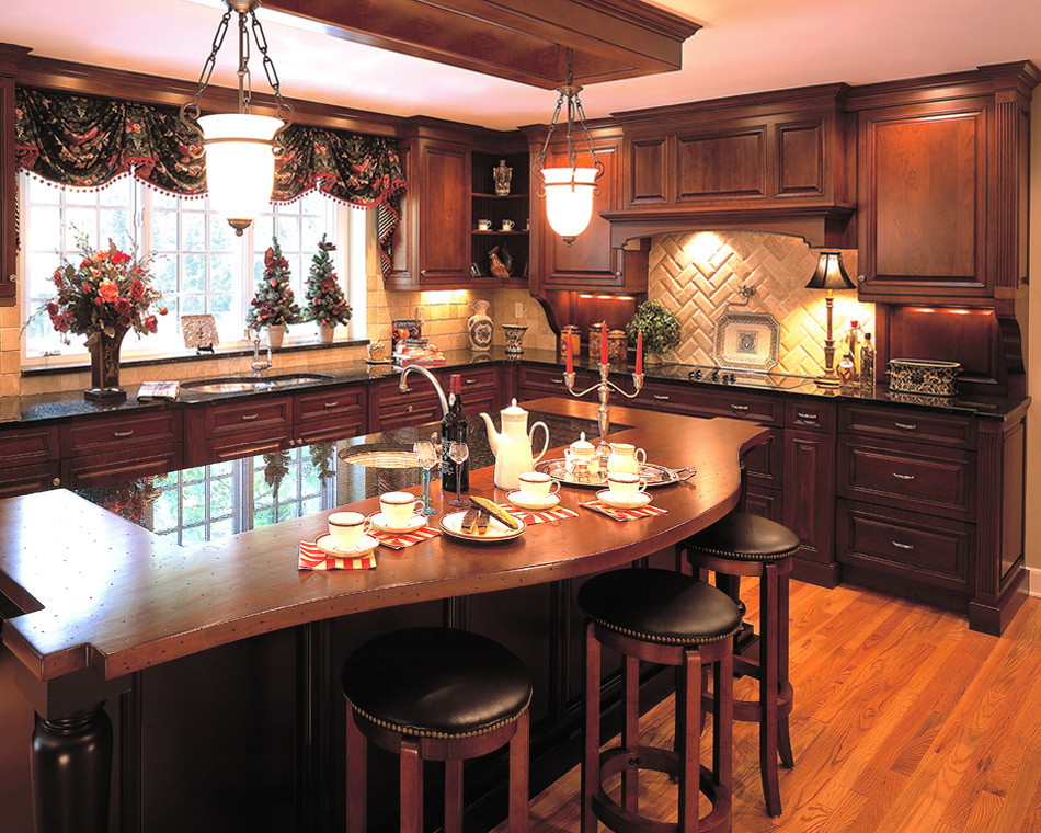 Bild på ett kök, med en köksö, luckor med upphöjd panel, skåp i mörkt trä, granitbänkskiva, stänkskydd i tunnelbanekakel, vitt stänkskydd och ljust trägolv