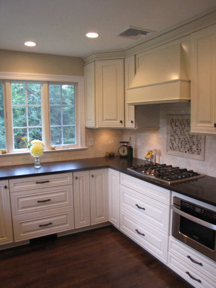 Klassisk inredning av ett avskilt, mellanstort u-kök, med en enkel diskho, luckor med upphöjd panel, vita skåp, bänkskiva i kvarts, beige stänkskydd, rostfria vitvaror och mörkt trägolv