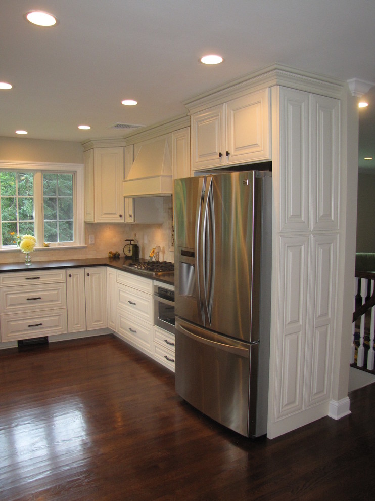 Mid-sized elegant u-shaped dark wood floor enclosed kitchen photo in New York with a single-bowl sink, raised-panel cabinets, white cabinets, quartz countertops, beige backsplash, stainless steel appliances and no island