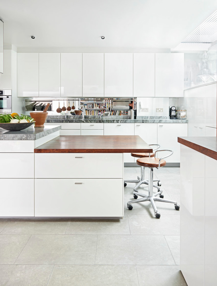 Moderne Küche mit flächenbündigen Schrankfronten, weißen Schränken, Rückwand aus Spiegelfliesen und Kücheninsel in London