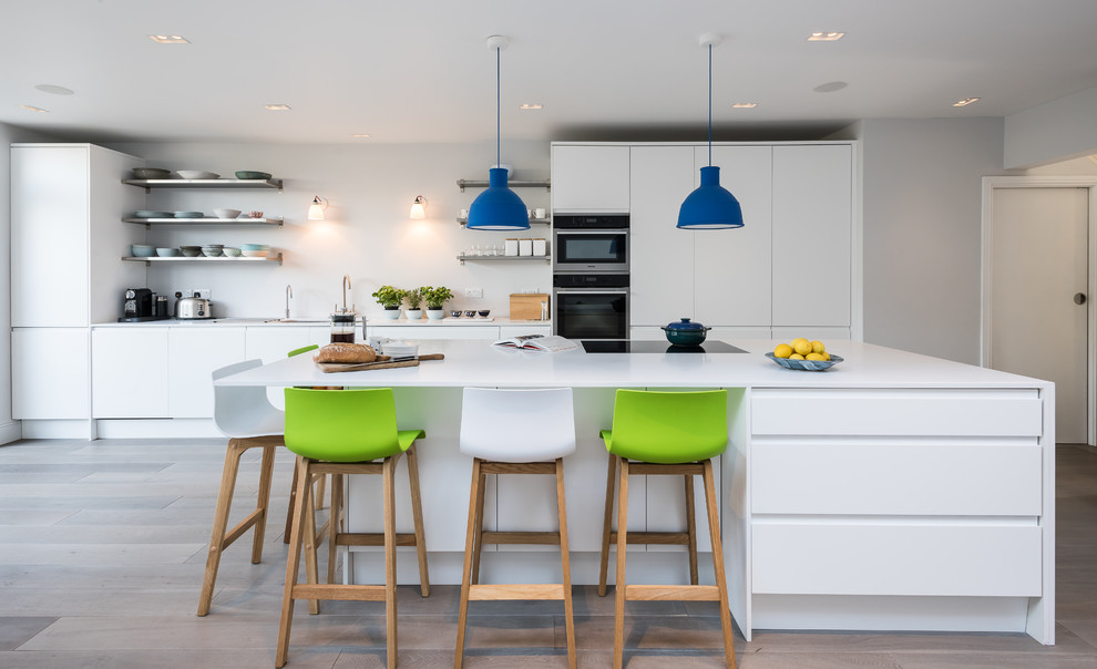 Immagine di una grande cucina moderna con ante lisce, ante bianche, elettrodomestici in acciaio inossidabile e parquet chiaro