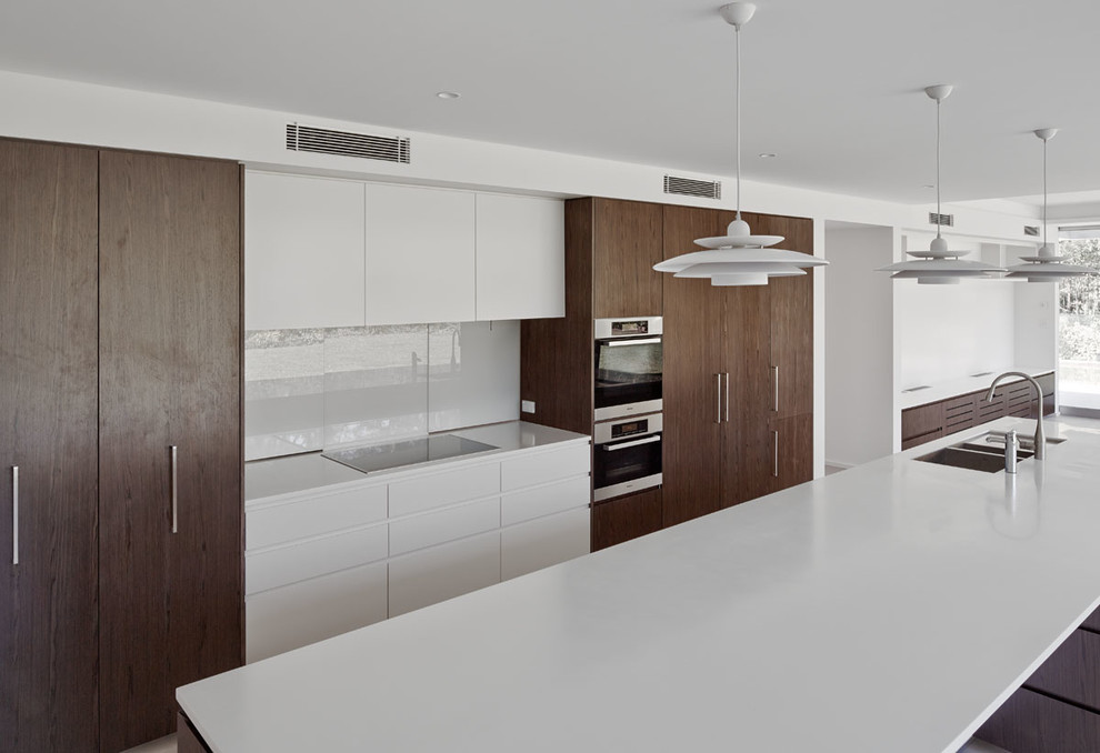 Стильный дизайн: прямая кухня в стиле модернизм с кладовкой, двойной мойкой, темными деревянными фасадами, белым фартуком и островом - последний тренд