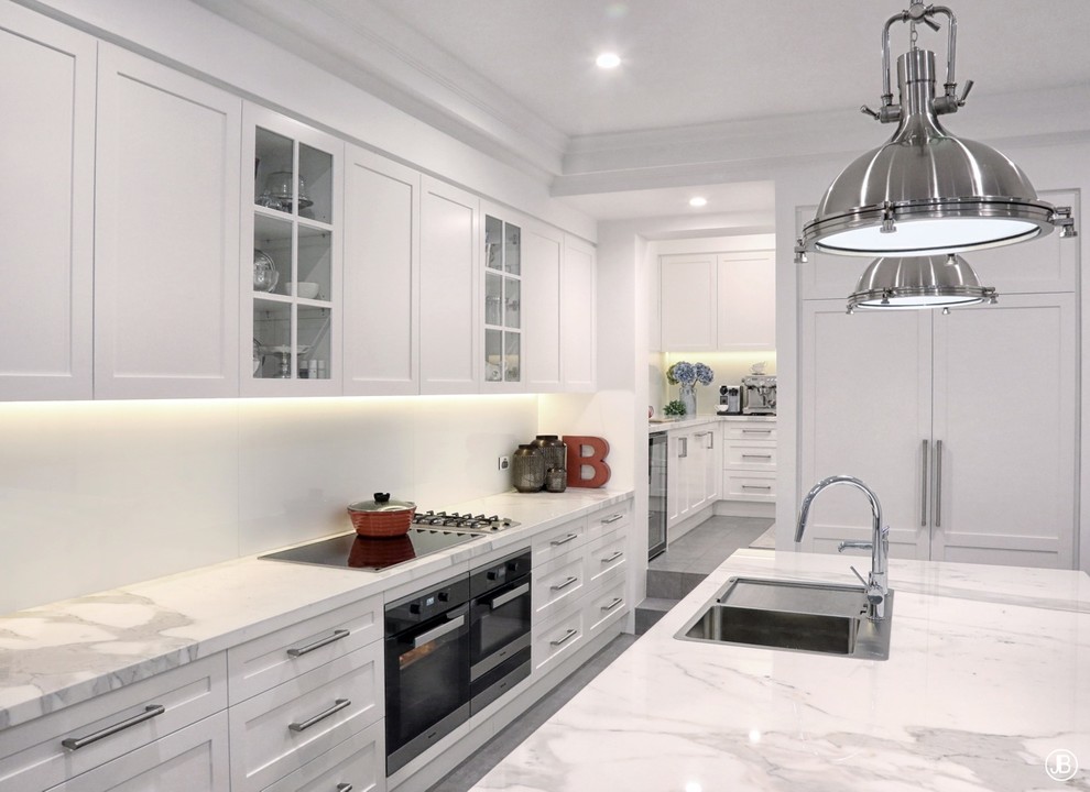 Photo of a modern kitchen in Sydney with a double-bowl sink, shaker cabinets, white cabinets, marble worktops, white splashback, glass sheet splashback, stainless steel appliances, ceramic flooring, an island, grey floors and white worktops.