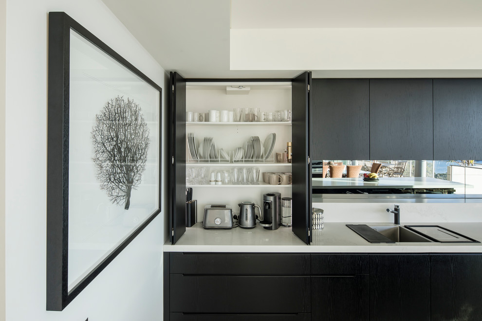 Esempio di una cucina minimalista di medie dimensioni con lavello sottopiano, ante nere, top in quarzo composito, paraspruzzi a specchio, elettrodomestici in acciaio inossidabile, pavimento in gres porcellanato, pavimento bianco e top bianco