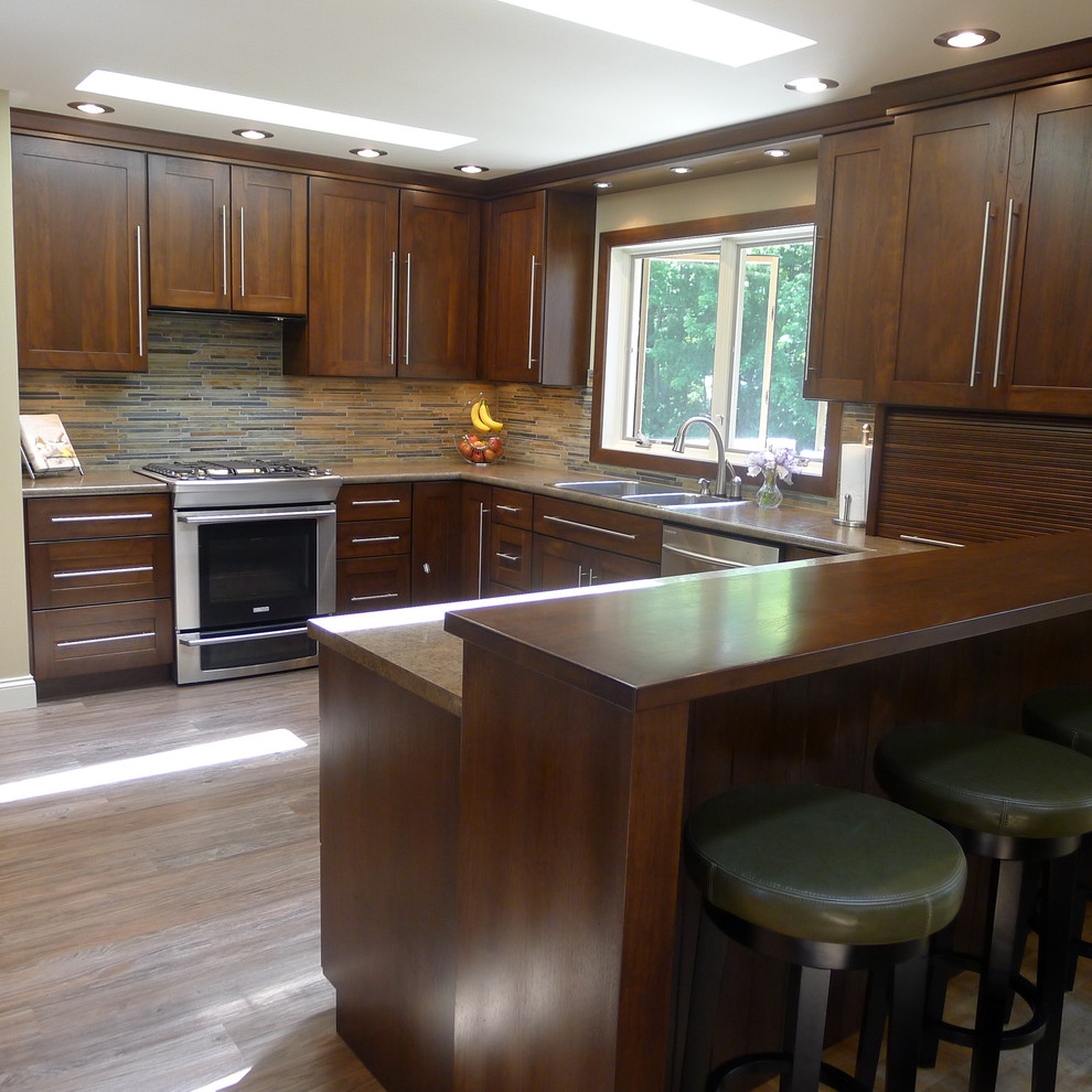 Example of a classic u-shaped enclosed kitchen design in Indianapolis with a drop-in sink, shaker cabinets, medium tone wood cabinets, laminate countertops, multicolored backsplash, matchstick tile backsplash and stainless steel appliances