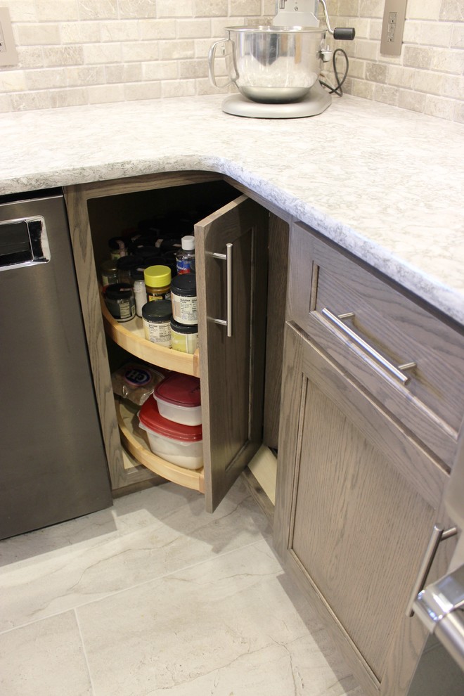 Inredning av ett klassiskt mellanstort grå grått kök, med en undermonterad diskho, släta luckor, grå skåp, bänkskiva i kvarts, grått stänkskydd, stänkskydd i kalk, rostfria vitvaror, klinkergolv i keramik, en köksö och grått golv