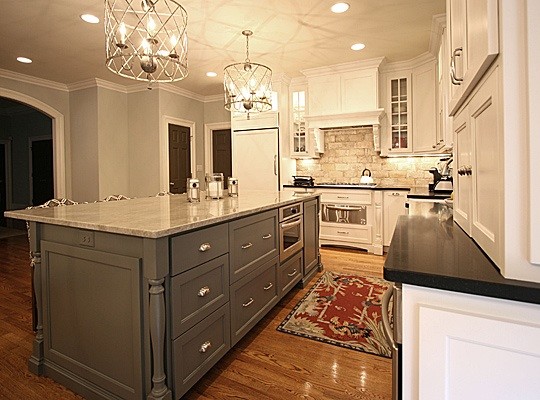 Eat-in kitchen - large transitional l-shaped medium tone wood floor eat-in kitchen idea in Charlotte with a farmhouse sink, recessed-panel cabinets, white cabinets, granite countertops, beige backsplash, ceramic backsplash and an island