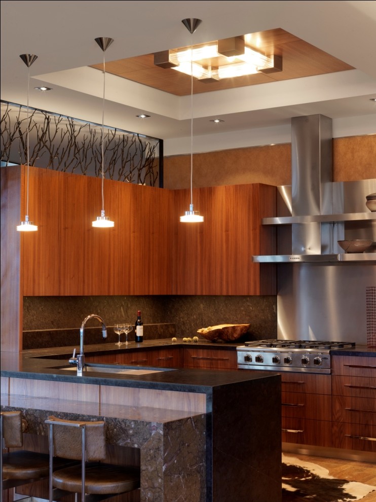 Imagen de cocina contemporánea con electrodomésticos de acero inoxidable, fregadero bajoencimera, armarios con paneles lisos, puertas de armario de madera en tonos medios y barras de cocina