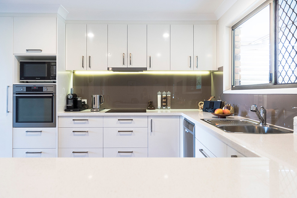This is an example of a medium sized industrial u-shaped kitchen/diner in Brisbane with a built-in sink, flat-panel cabinets, white cabinets, copper worktops, white splashback, glass sheet splashback, white appliances, medium hardwood flooring, an island, white floors and white worktops.