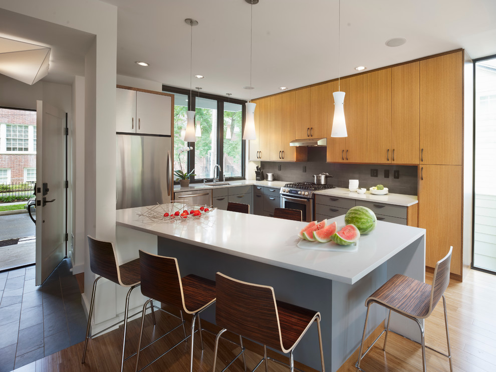 Ejemplo de cocina moderna con armarios con paneles lisos, puertas de armario de madera clara y electrodomésticos de acero inoxidable