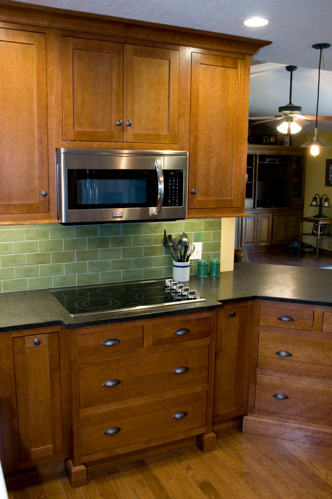 Foto på ett mellanstort amerikanskt kök, med en rustik diskho, skåp i mellenmörkt trä, granitbänkskiva, grönt stänkskydd, rostfria vitvaror, ljust trägolv och en halv köksö