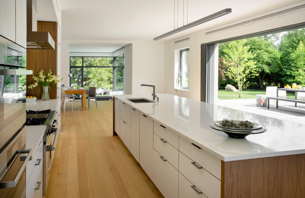 Inspiration pour une cuisine parallèle minimaliste avec un sol en bois brun, îlot, un sol marron et un plan de travail blanc.