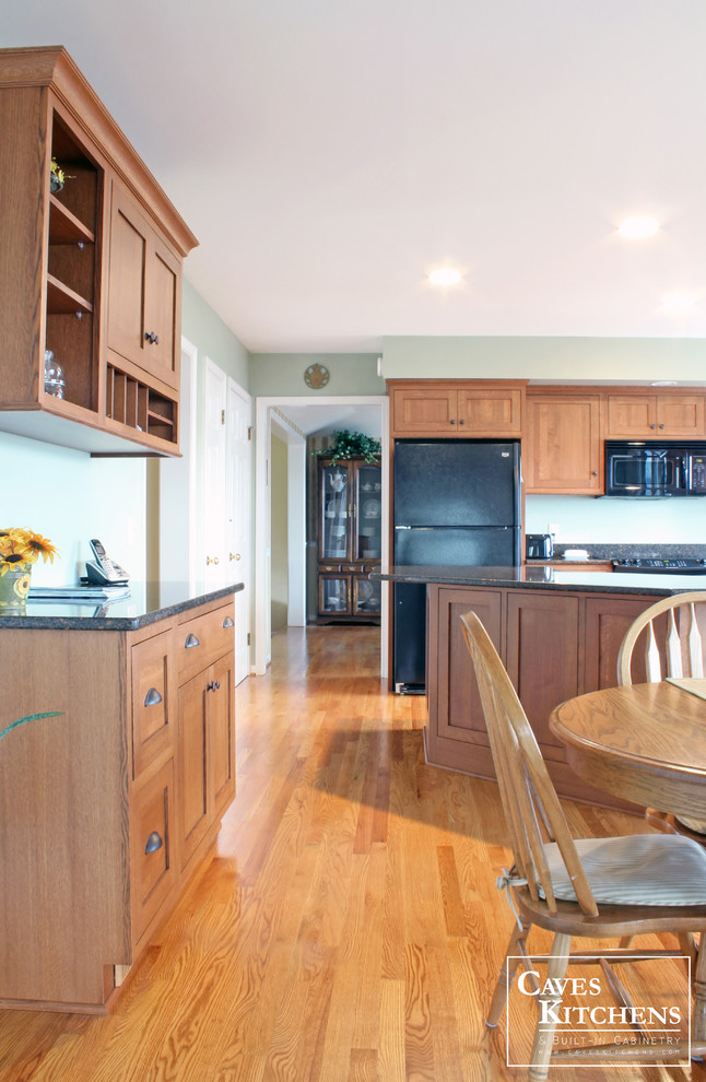 Bild på ett mellanstort vintage kök, med en undermonterad diskho, luckor med infälld panel, skåp i mellenmörkt trä, bänkskiva i kvarts, flerfärgad stänkskydd, stänkskydd i sten, svarta vitvaror, mellanmörkt trägolv och en köksö