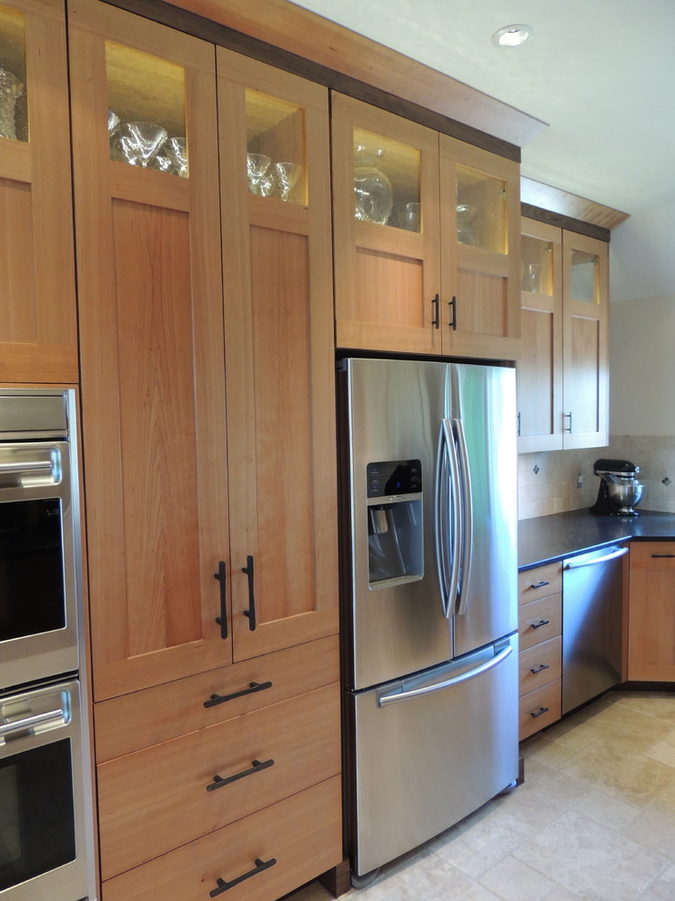 Modern inredning av ett kök, med en undermonterad diskho, släta luckor, skåp i mellenmörkt trä, granitbänkskiva, beige stänkskydd, stänkskydd i tunnelbanekakel och rostfria vitvaror
