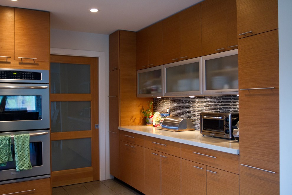 Medium sized modern u-shaped open plan kitchen in Vancouver with a submerged sink, flat-panel cabinets, engineered stone countertops, brown splashback, glass sheet splashback, stainless steel appliances, porcelain flooring, a breakfast bar and medium wood cabinets.