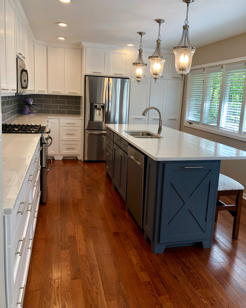 Inspiration for a traditional kitchen in Atlanta with a built-in sink, shaker cabinets, white cabinets, engineered stone countertops, grey splashback, metro tiled splashback, stainless steel appliances, medium hardwood flooring, an island and grey worktops.