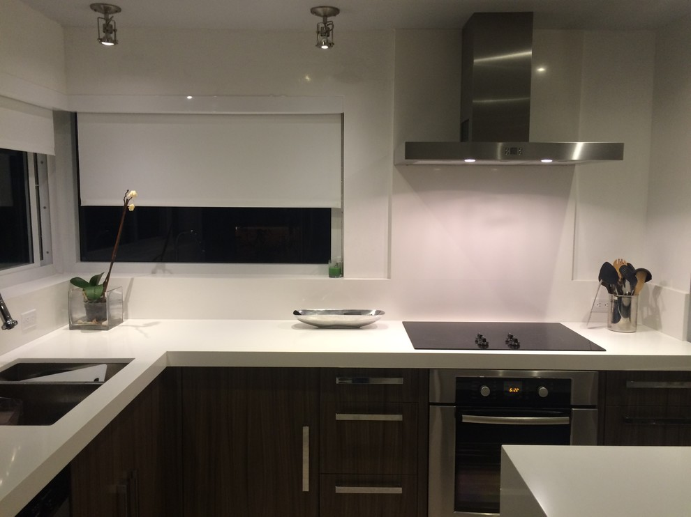 This is an example of a coastal l-shaped kitchen in Miami with engineered stone countertops and white splashback.