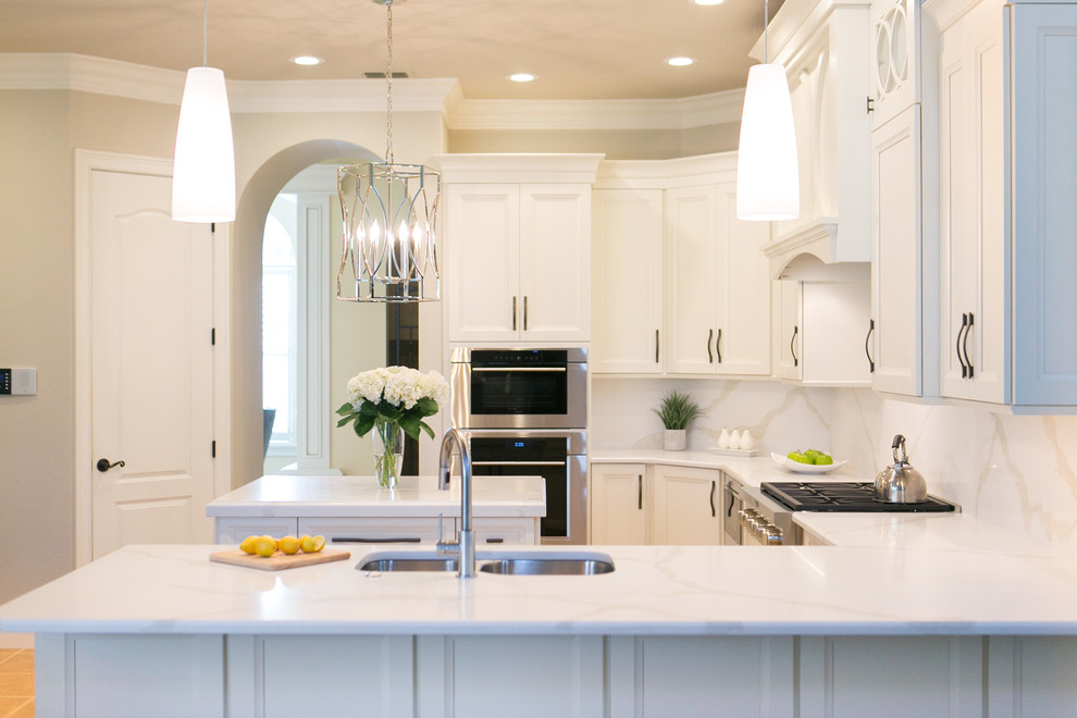 Example of a mid-sized transitional u-shaped open concept kitchen design in Orlando with an undermount sink, recessed-panel cabinets, white cabinets, quartzite countertops, white backsplash, stone slab backsplash, stainless steel appliances and a peninsula
