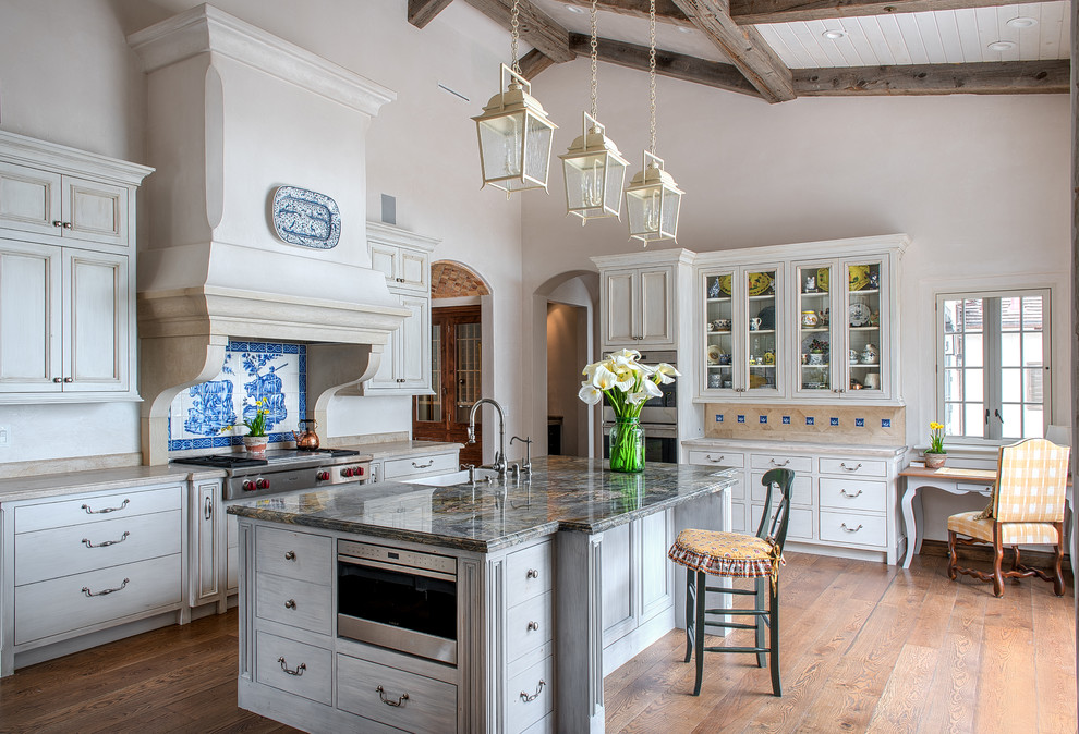 Example of a large farmhouse l-shaped light wood floor and brown floor enclosed kitchen design in San Francisco with glass-front cabinets, beige cabinets, multicolored backsplash, stainless steel appliances, an island, a farmhouse sink, quartzite countertops, ceramic backsplash and beige countertops
